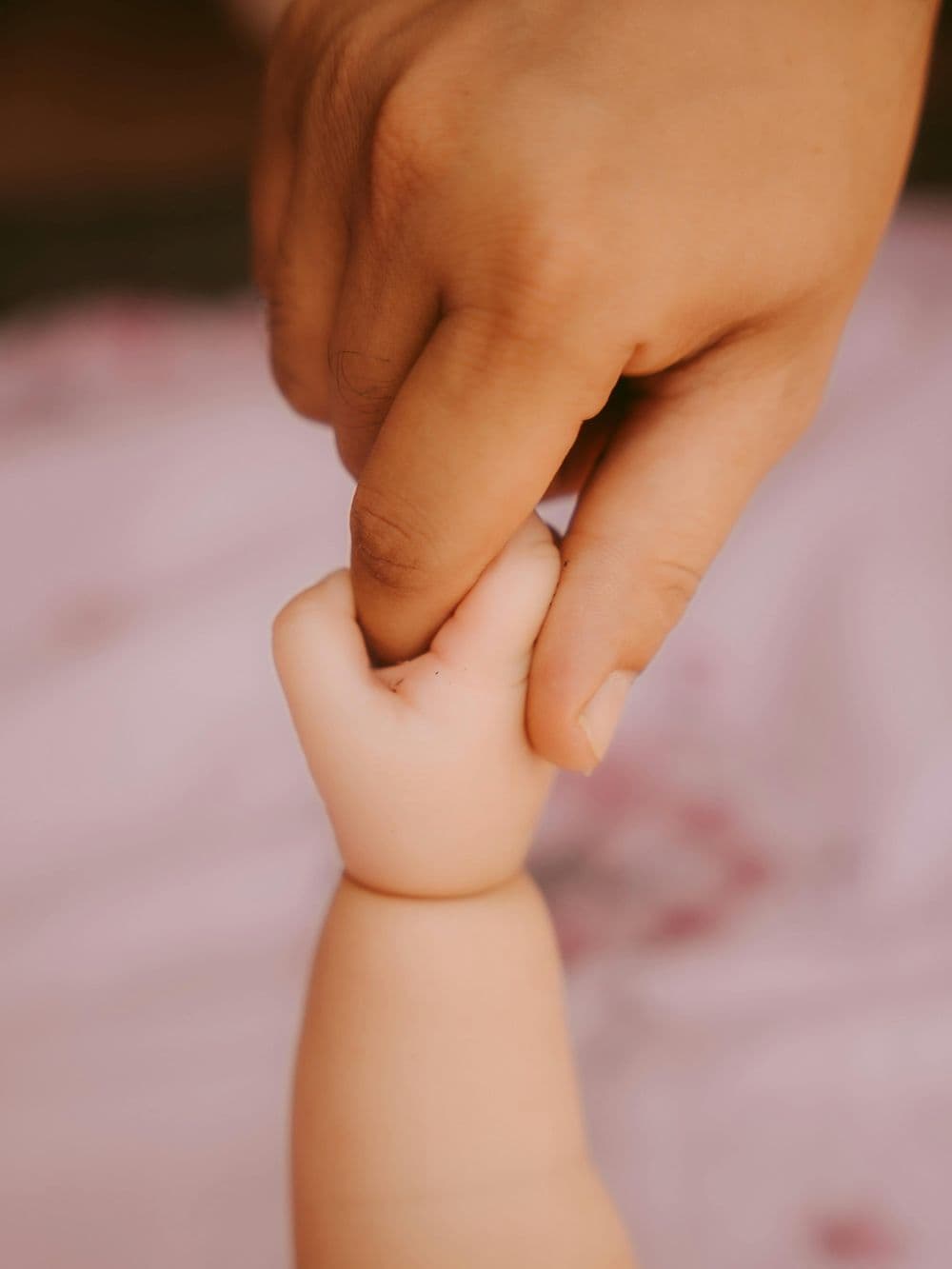 A small child's hand holding a parent's finger