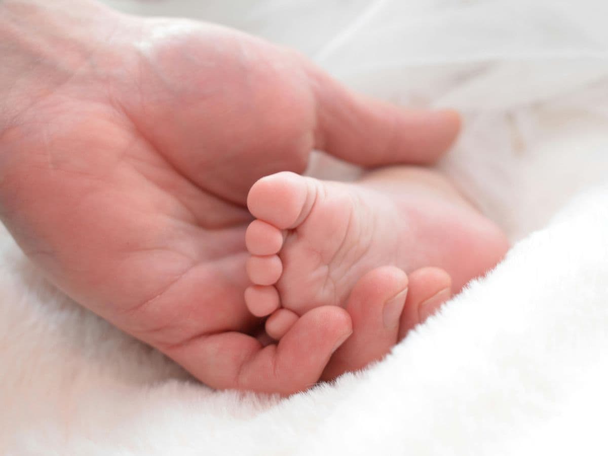 A parent’s hand cradling a baby’s foot